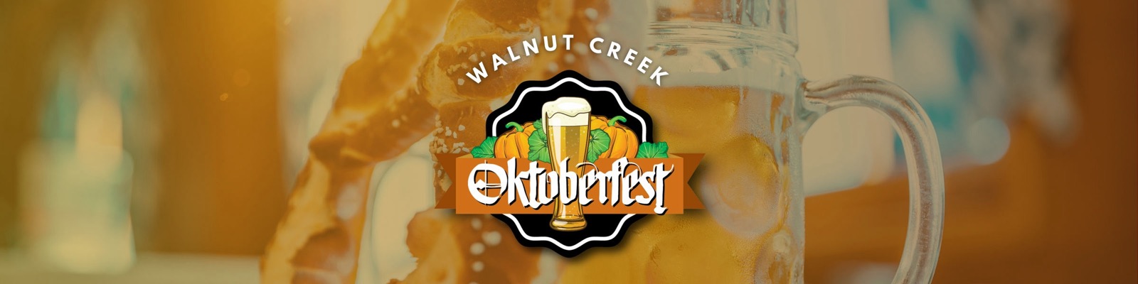 Walnut Creek Oktoberfest banner — the festival logo, a beer glass framed by pumpkins on a black badge with an orange Oktoberfest ribbon.